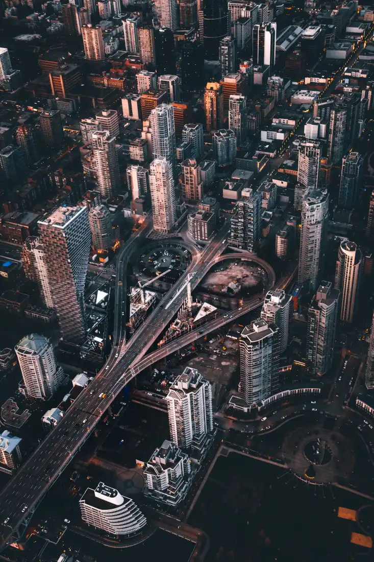 高空俯瞰黄昏时分密集的都市高楼群与纵横交错的城市立交