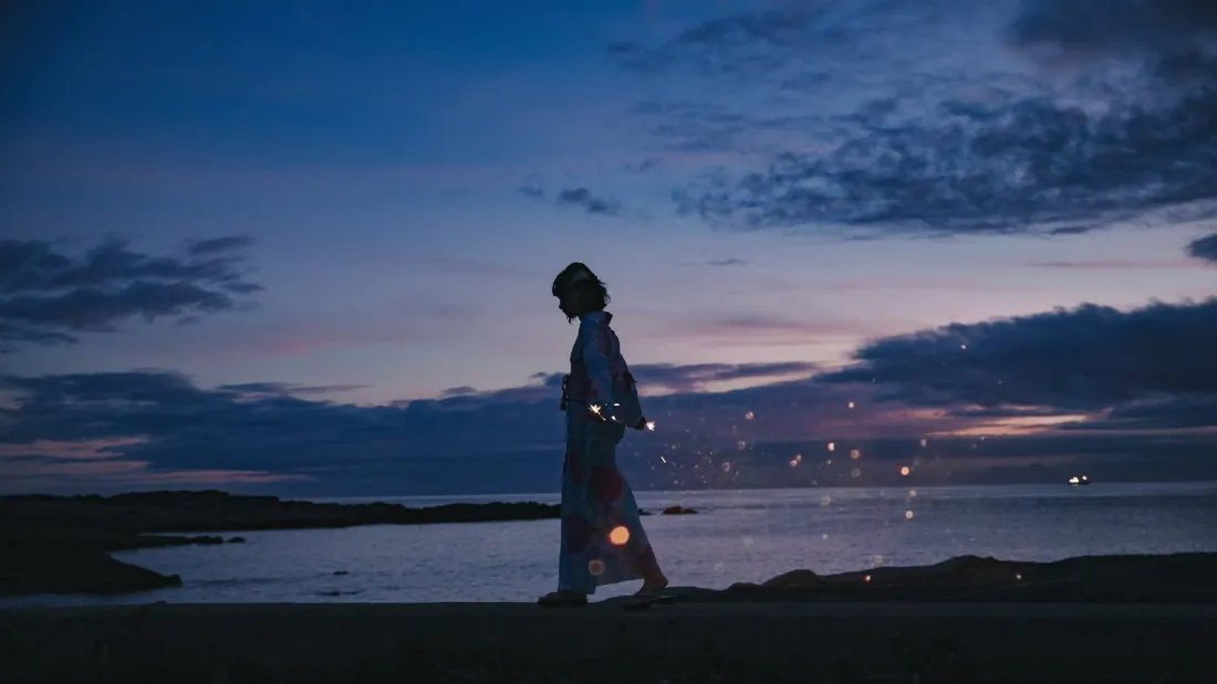 暮色海岸边，身着长裙的少女剪影缓步前行，海面泛着细碎光点。