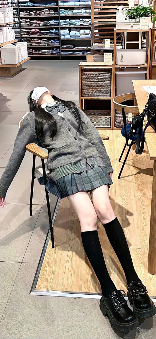 穿灰色JK制服的女生后仰靠在店内椅子上，头部被白色物体遮挡。