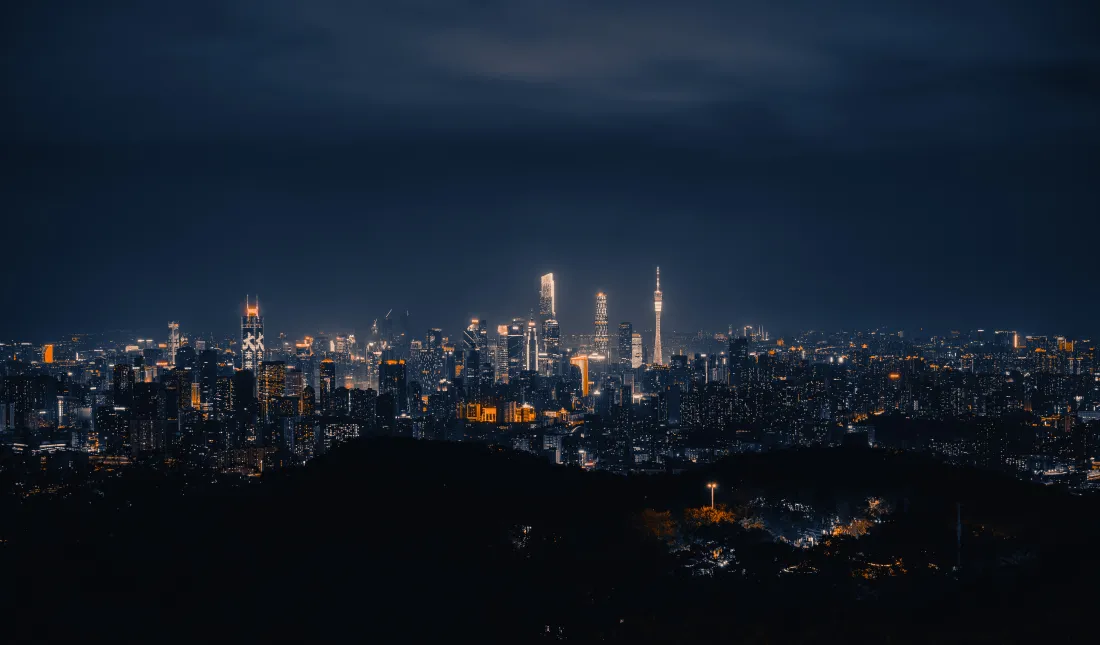 高空俯瞰夜幕下的城市天际线，摩天楼灯火在暗蓝夜空下璀璨延展