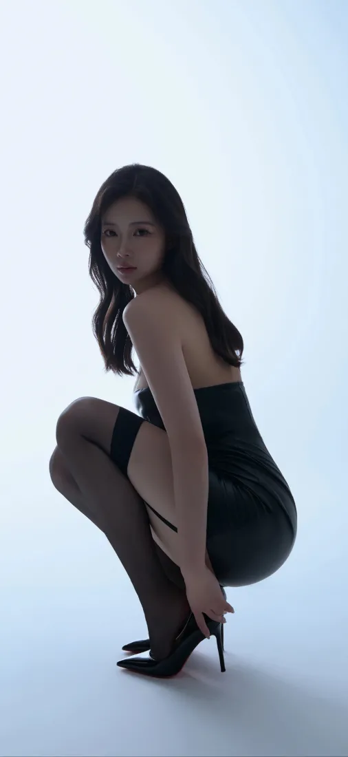 浅白背景下，穿黑裙黑丝高跟鞋的长发女性蹲姿回头看向镜头。