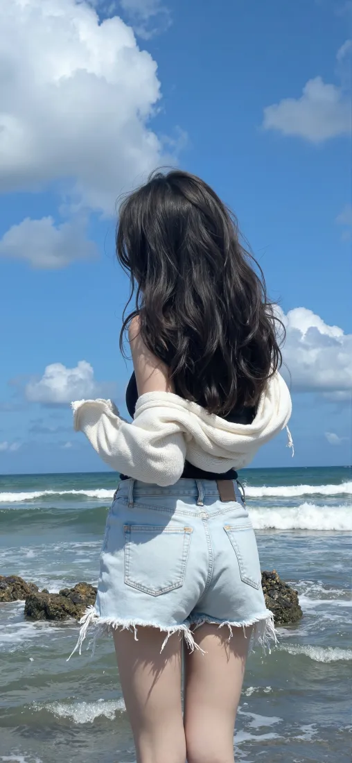 长发女生背对镜头站在海边浅滩，望向蓝天白云与翻涌海浪
