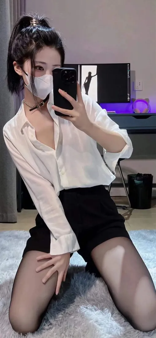 扎高马尾戴口罩的女生穿白衬衫黑短裤黑丝，跪坐毛绒地毯上举手机对镜自拍