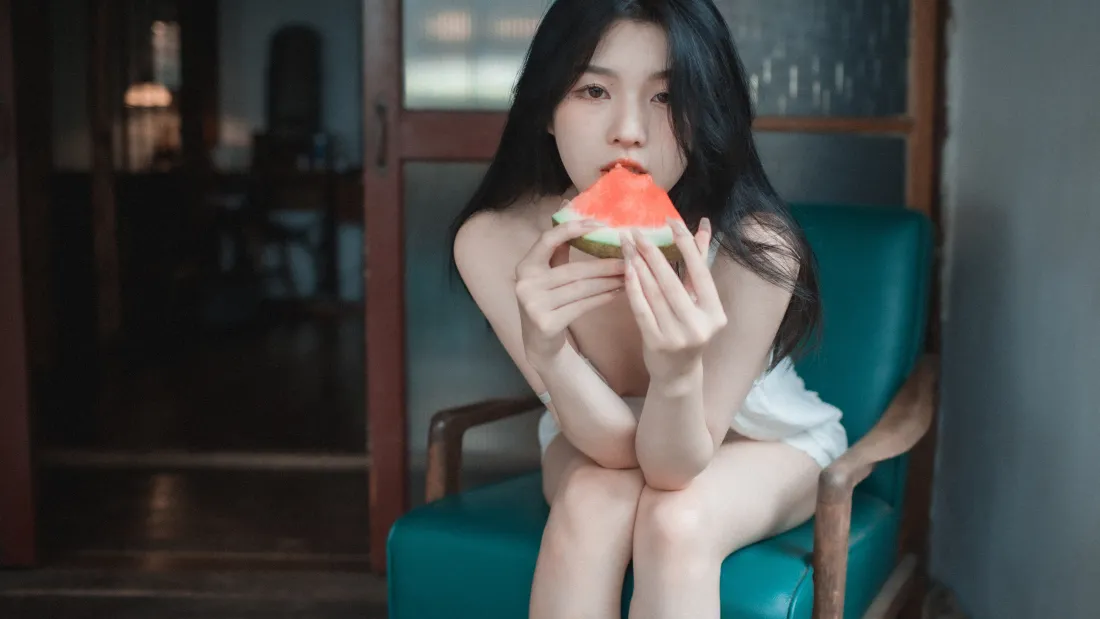4k美女壁纸|吃西瓜美女背景图片 - 清新风「哲风壁纸」 长发年轻女子裹着白色浴巾坐在青绿色扶手椅上,双手捧着西瓜片凑近嘴边。