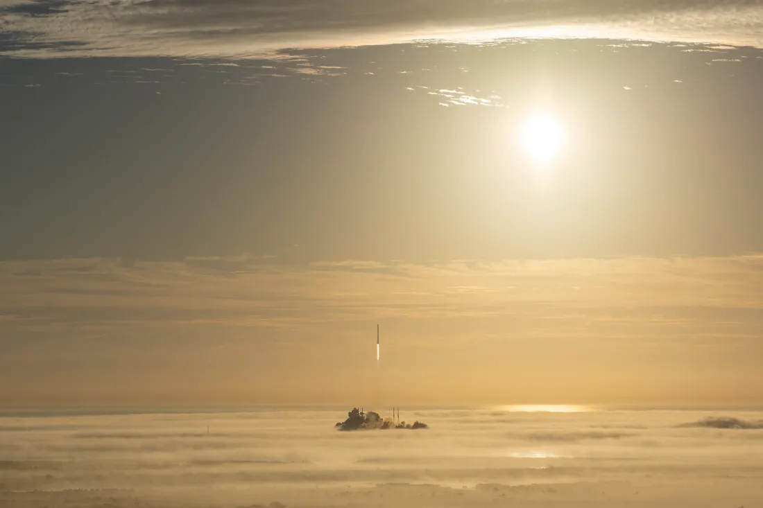 日出时分云海之上，SpaceX星舰火箭从海上平台升空，暖金色阳光铺满天际