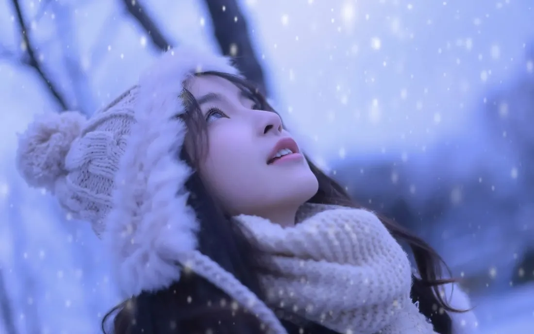 飘雪冬日户外，戴毛绒针织帽与围巾的少女仰头望雪，氛围梦幻柔和。