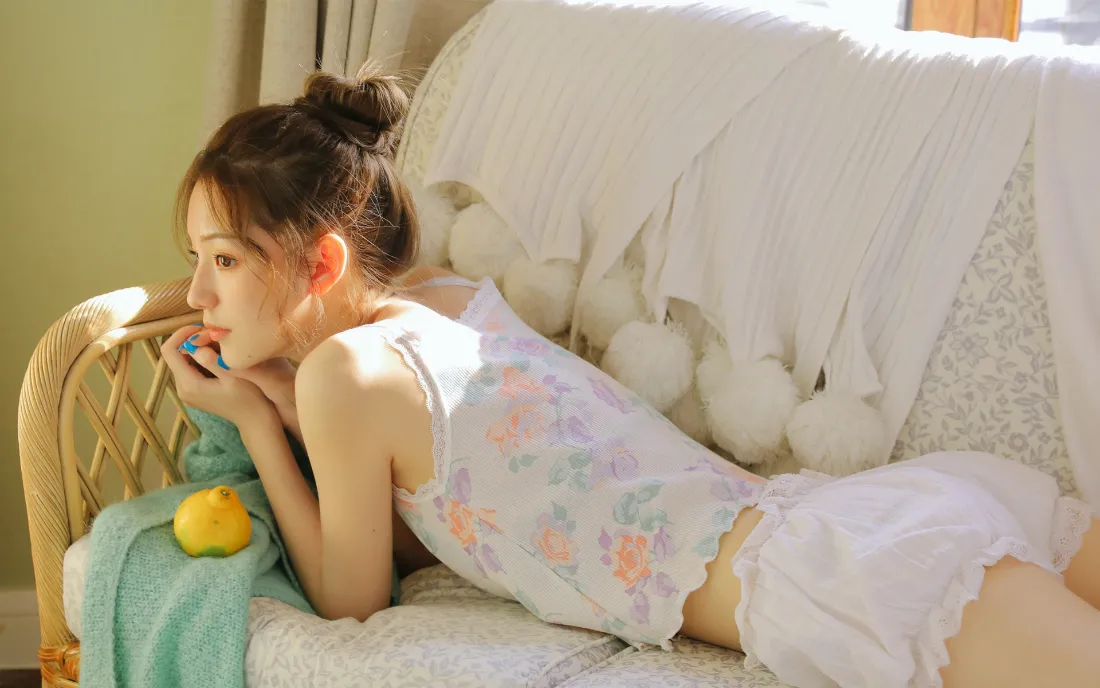 2k少女卧室|清新家居背景图片 - 柠檬兔子场景「哲风壁纸」 扎丸子头的年轻女子身着印花家居服,慵懒趴在藤编沙发上,身侧放着柠檬