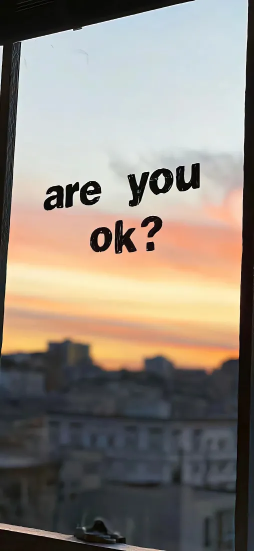 窗玻璃上印着are you ok?字样，窗外是黄昏橙粉渐变天空与模糊城市建筑。