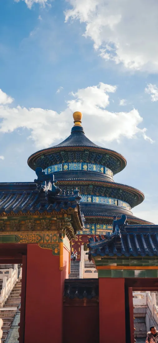 仰拍视角下，天坛祈年殿在蓝天白云映衬下，前方搭配朱红宫墙与附属古建。