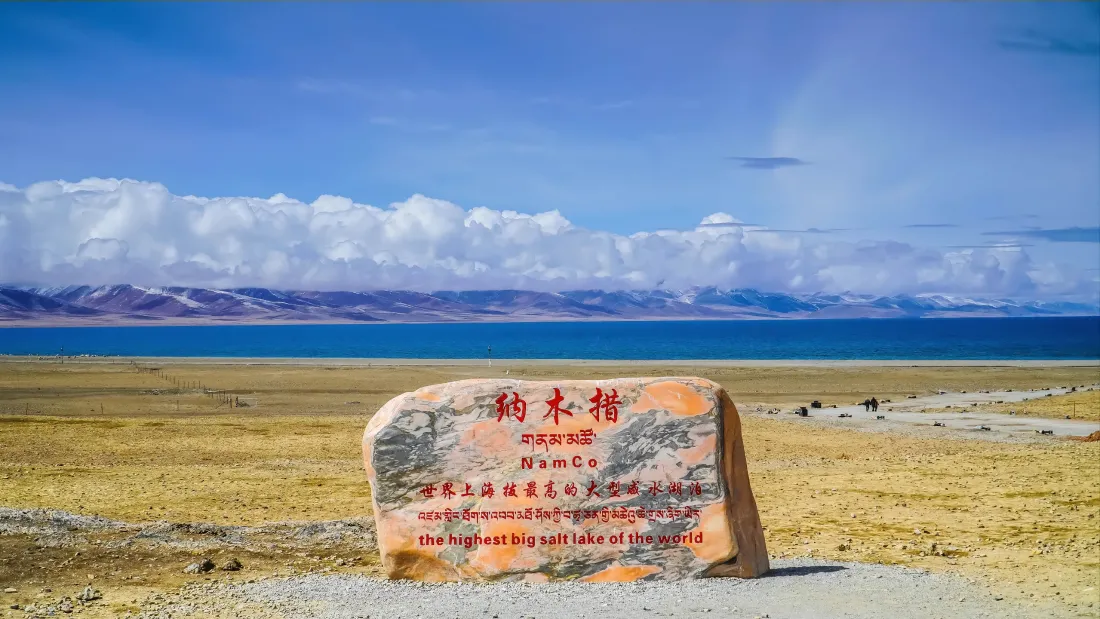3k纳木错壁纸|拉萨背景图片 - 高原圣湖「哲风壁纸」 纳木错湖畔立有刻字石碑,远处是湛蓝湖水、雪山与蓝天白云。
