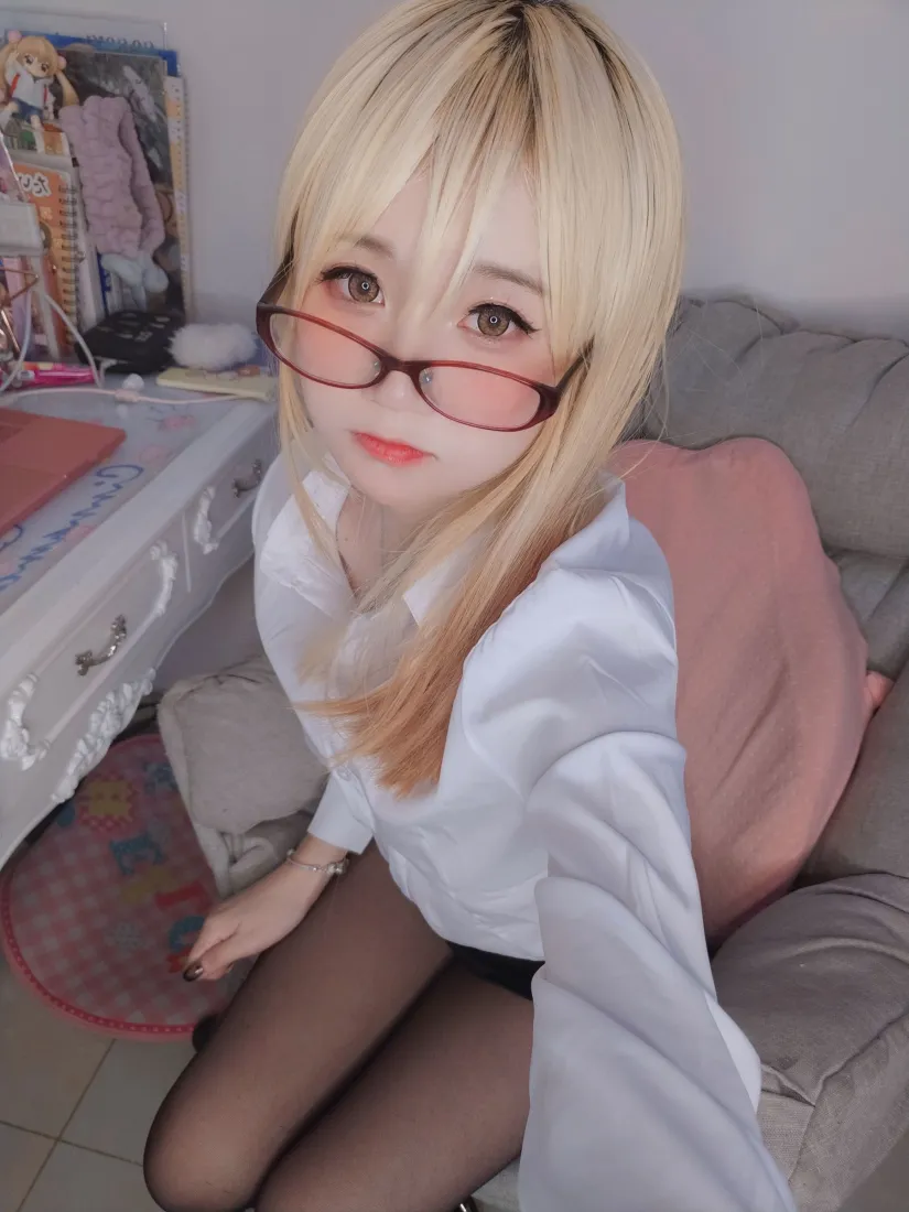 戴棕框眼镜的金发少女穿白衬衫黑丝，在居家沙发上自拍。