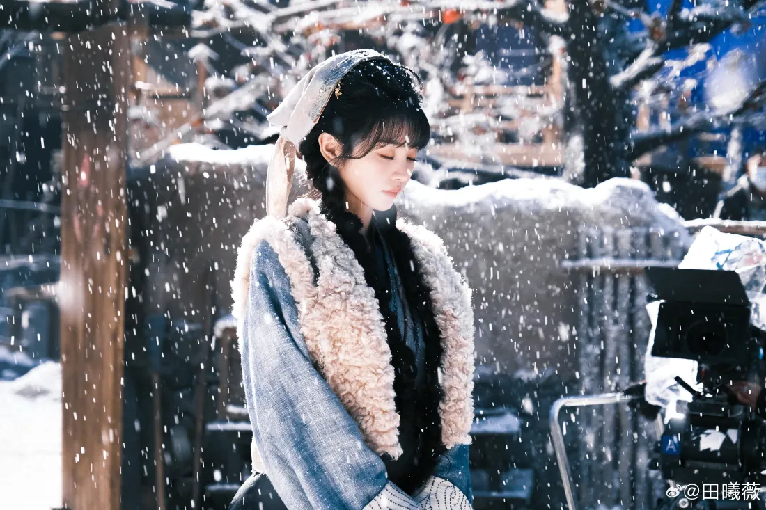 飘雪冬日里，田曦薇身着带毛绒领的蓝色外套，低头静立在积雪的院落中。
