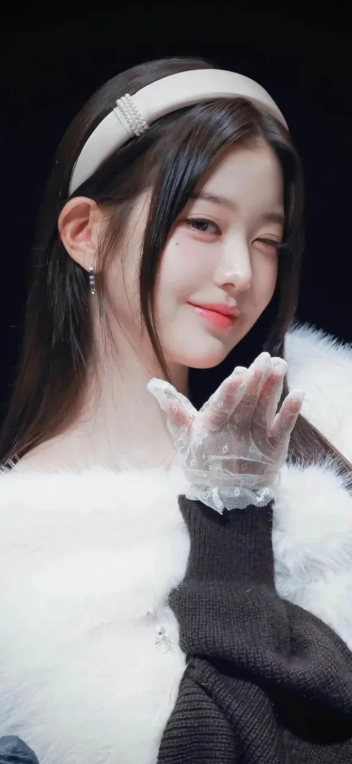 黑长直女生戴白色发箍与毛绒披肩，眨眼送飞吻，黑底人像