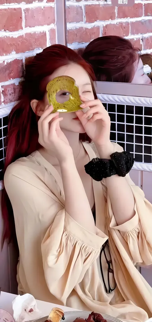 红发赵露思穿米色居家服，手持黄色眼膜单眼wink，背景为红砖墙。