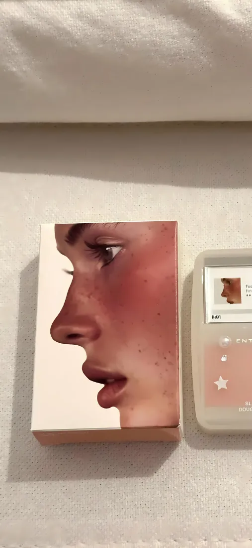 浅白墙面上摆放印有人物侧脸的美妆盒与带星星装饰的小物件