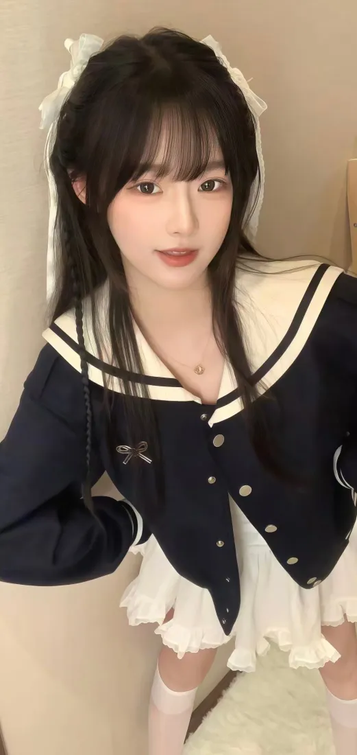 室内黑发少女身着藏青镶白边水手服，搭配白色蕾丝发饰与白袜，面向镜头。