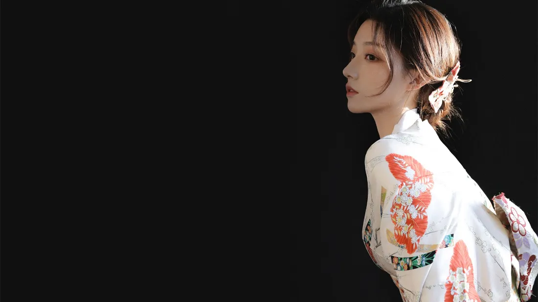黑色背景下，身着白底红花纹和服的年轻女子侧身回望的半身人像