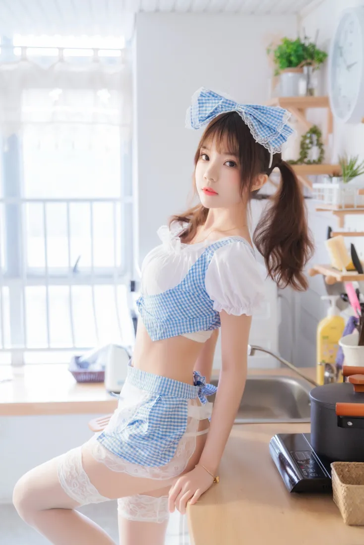 明亮居家厨房内，双马尾少女身着蓝白格纹短款女仆装倚靠台面