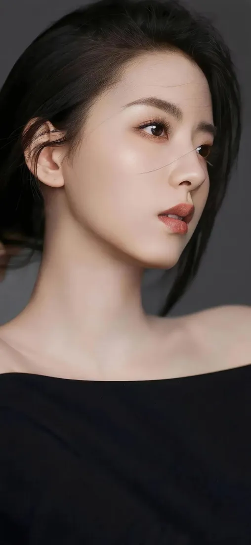 灰调背景下，黑衣露肩黑发美女侧脸望向画面右侧，气质沉静。