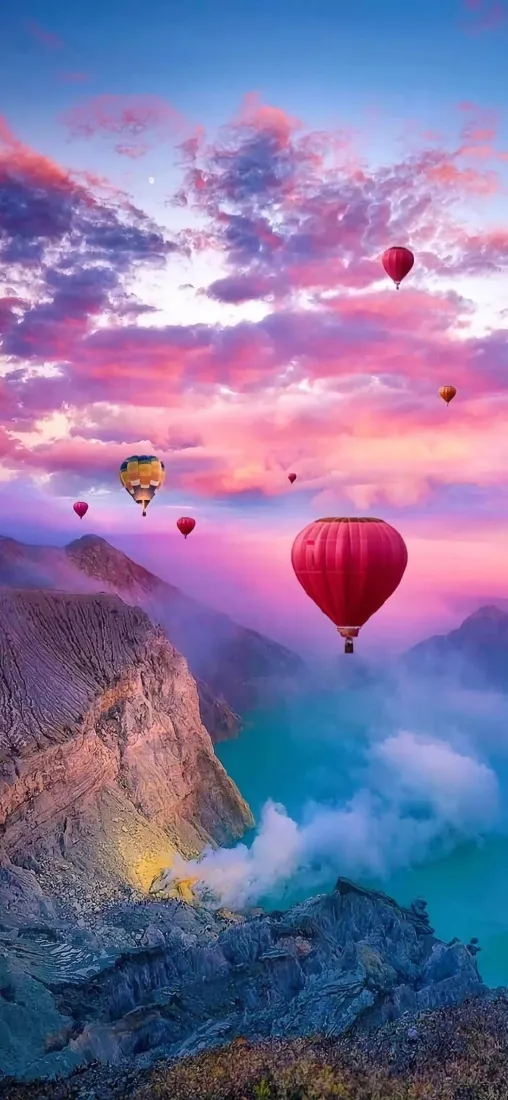 粉紫黄昏天空下，多只热气球漂浮在峡谷与青蓝色湖泊上空。
