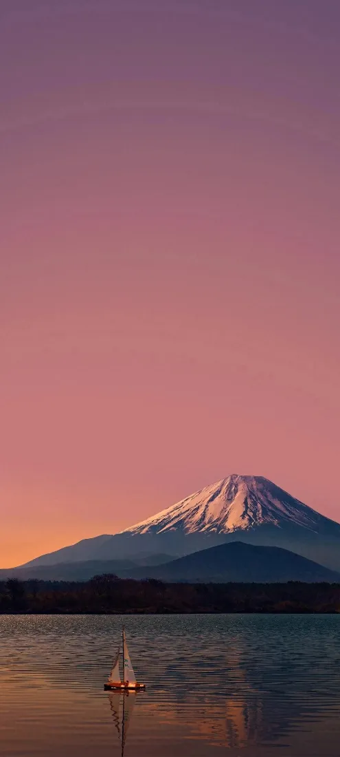 粉色黄昏下，富士山静立湖畔，湖面漂浮着一艘小帆船。