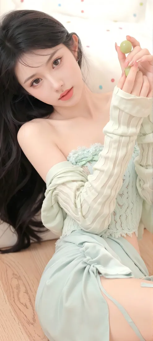 长发年轻女子身着浅绿套装，手持青提，倚靠在带彩点的浅色背景前。