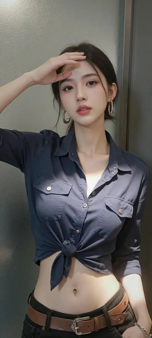 年轻女性身着打结深蓝露脐衬衫，佩戴大耳环，抬手置于额前，倚靠灰调墙面。