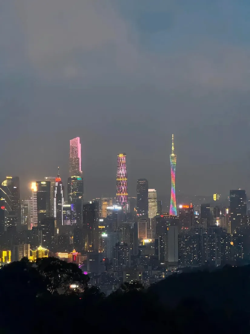 暮色下的广州城市天际线，亮灯的摩天建筑群与广州塔在灰蒙天色下铺展。
