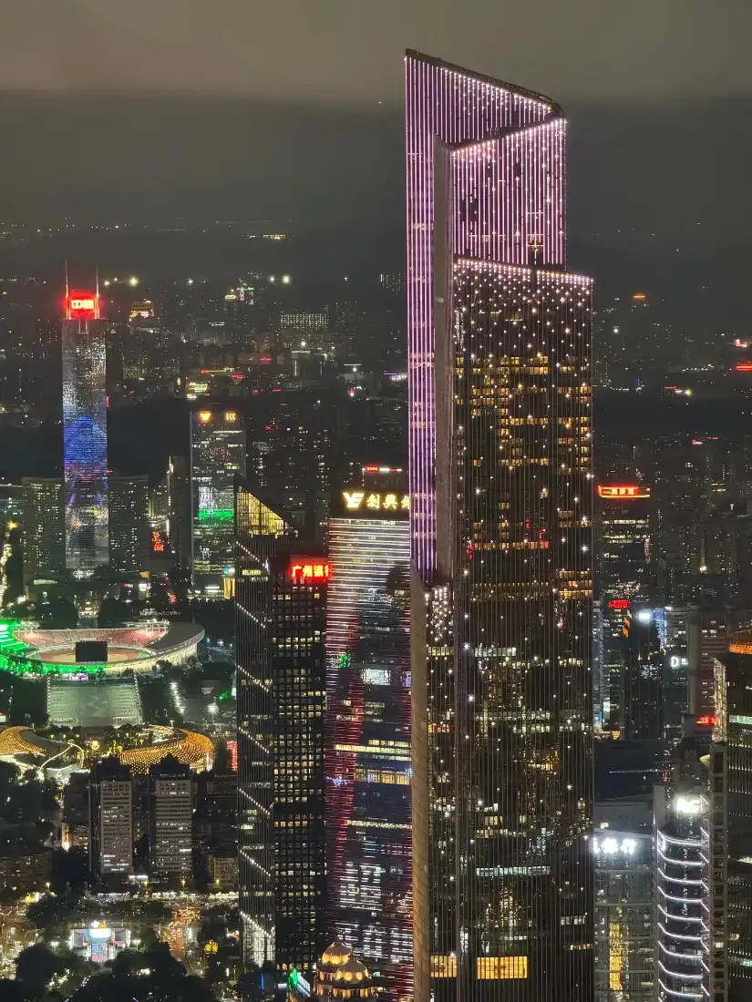 高空俯瞰的都市夜景，林立摩天大楼亮着多彩灯光，灯火璀璨。