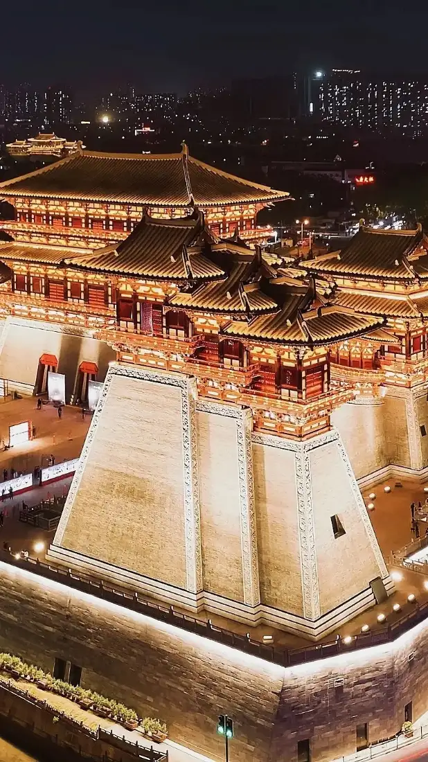 洛阳应天门夜景，暖黄灯光照亮中式古建筑，远处是城市灯火