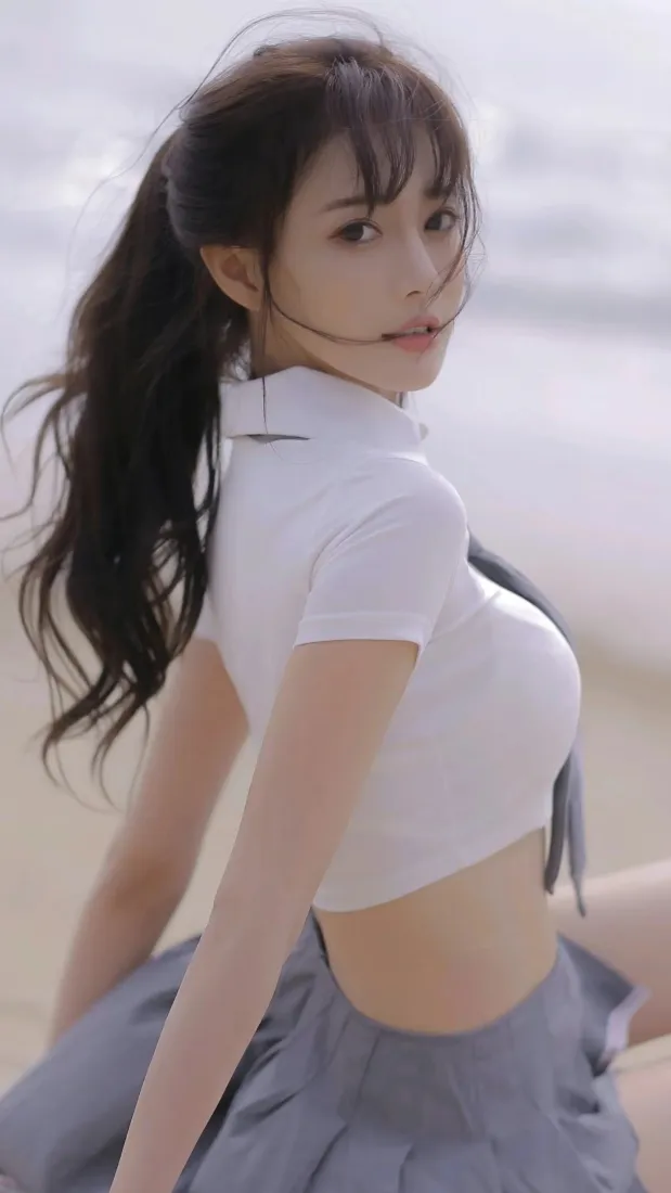 海边沙滩上扎马尾的白衣露脐装女生回眸望向镜头，背景虚化。