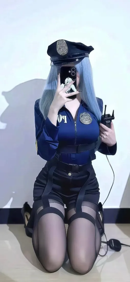 蓝发女性cos女警，跪姿对镜自拍，手持对讲机，白墙背景