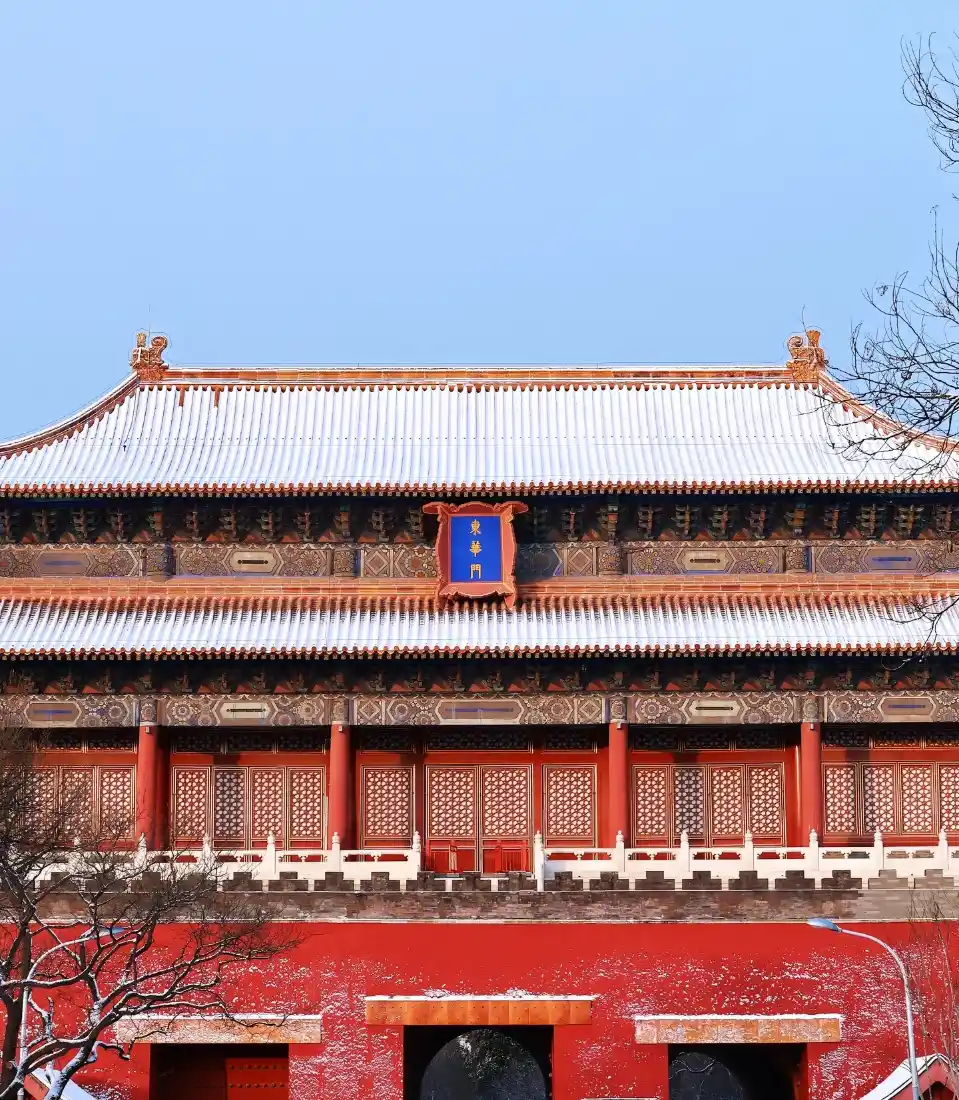 雪后故宫古建筑，红墙覆薄雪，琉璃瓦顶积白雪，上方是澄澈蓝天。