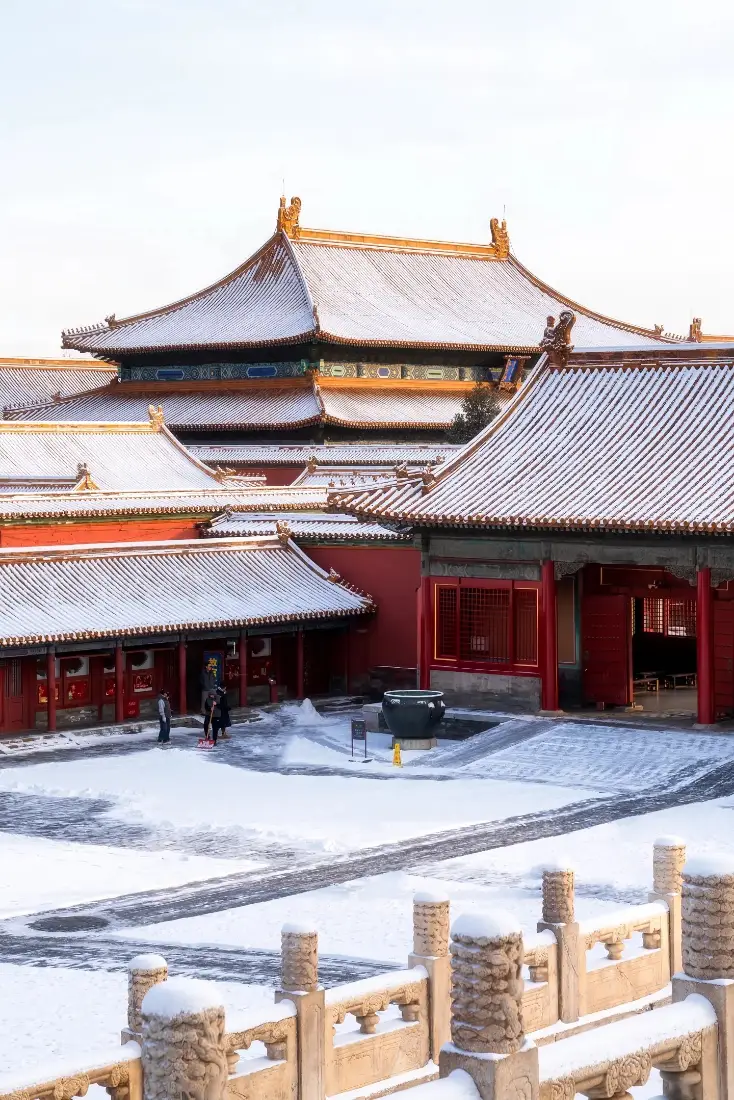 雪后故宫红墙黄瓦宫殿群，庭院覆雪，石栏前景，游人点缀。