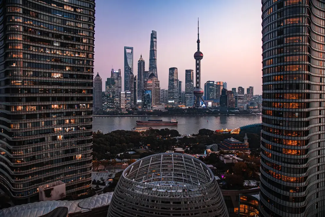 黄昏时分上海黄浦江畔陆家嘴摩天建筑群天际线，江面有货船，两侧高楼框景。