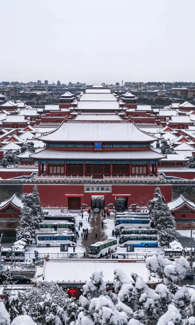 雪后俯瞰故宫中轴线，红墙金瓦覆白雪，古建群落气势恢宏。
