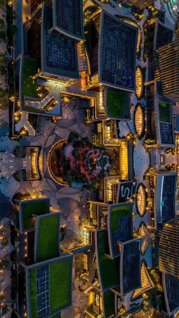 高空俯瞰西安夜景，建筑群灯火璀璨，屋顶绿植与暖黄灯光交织。