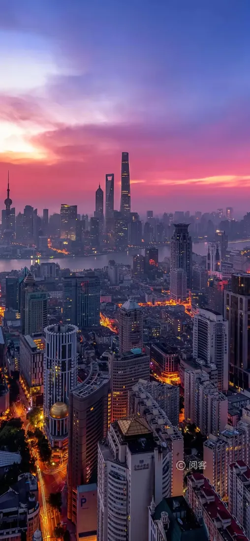 黄昏时分上海陆家嘴摩天建筑群航拍，粉紫晚霞晕染天际，城市暖灯初上