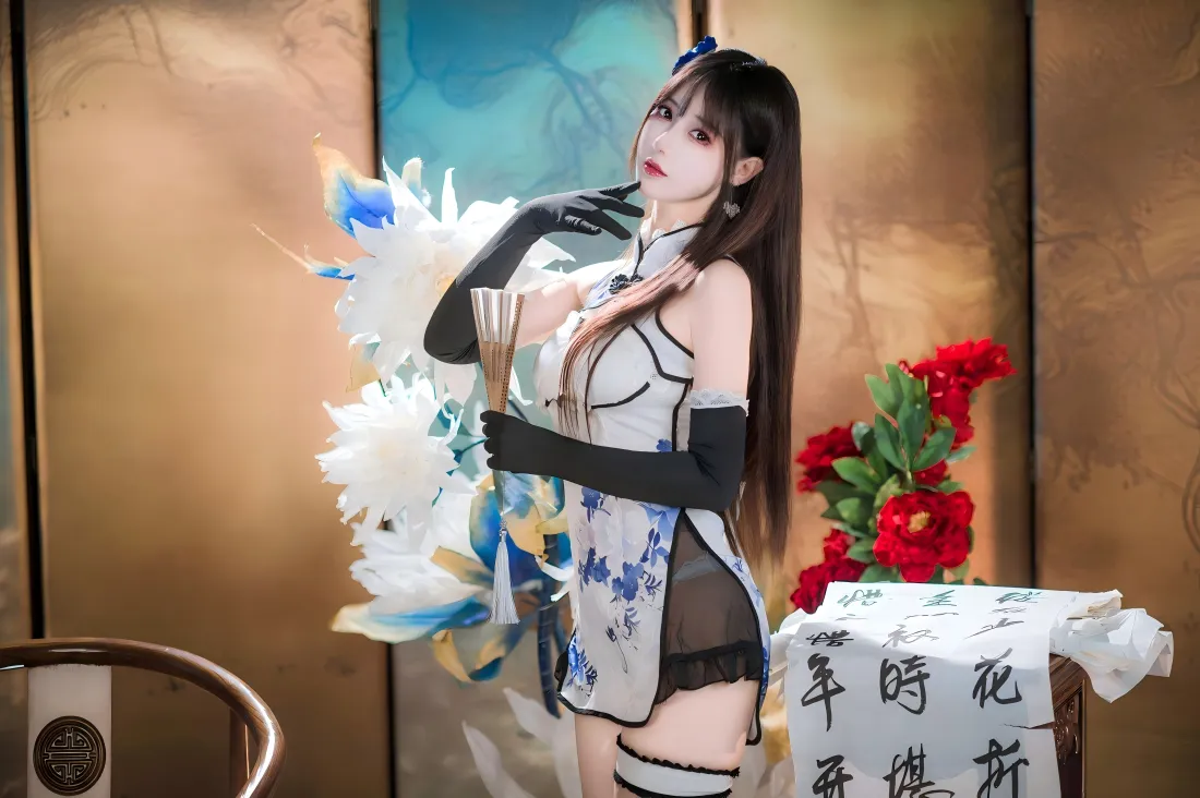 身着青花瓷短旗袍的长发女子，手持毛笔立于中式屏风前，旁有红花与书法纸。