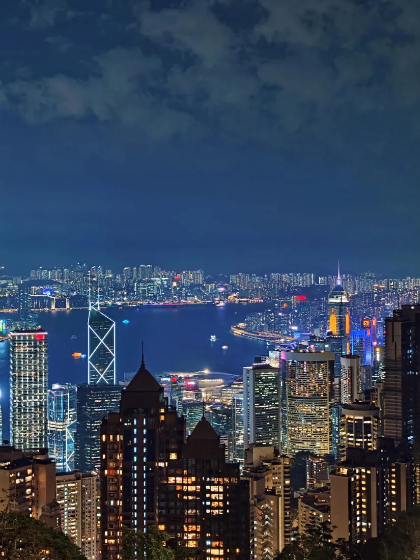 高空俯瞰香港维多利亚港夜景，两岸摩天大楼灯火璀璨，港湾水面倒映灯光。