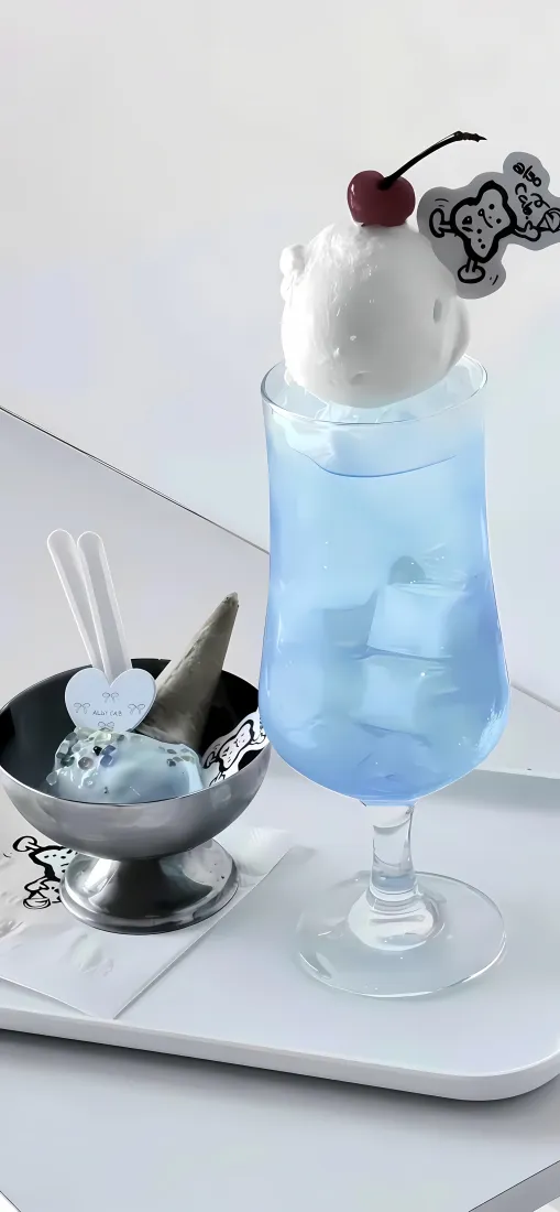 白色托盘上摆放着蓝色冰饮与金属小碗盛装的冰淇淋，顶部点缀樱桃与卡通装饰。