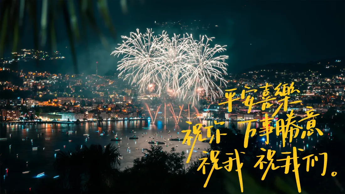 夜晚滨水城市上空绽放白色烟花，水面倒映城市灯火，右侧有黄色手写新年祝福文字。