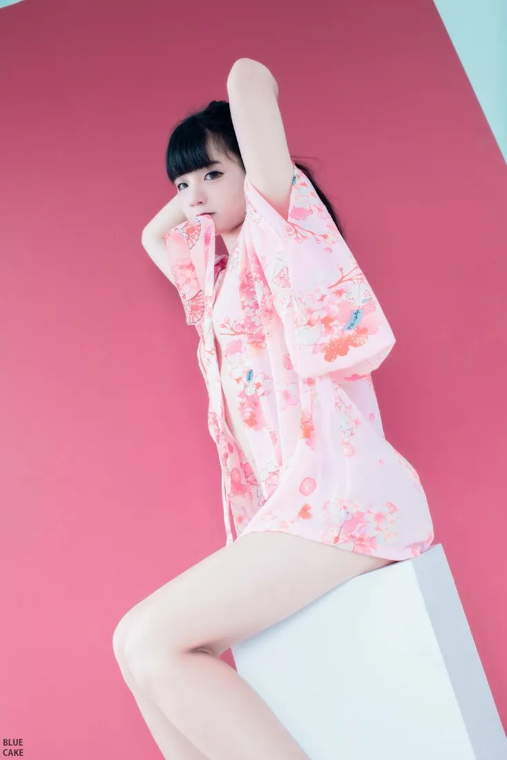 齐刘海黑长发少女身着粉色印花日系睡衣，在纯红色背景前摆拍写真