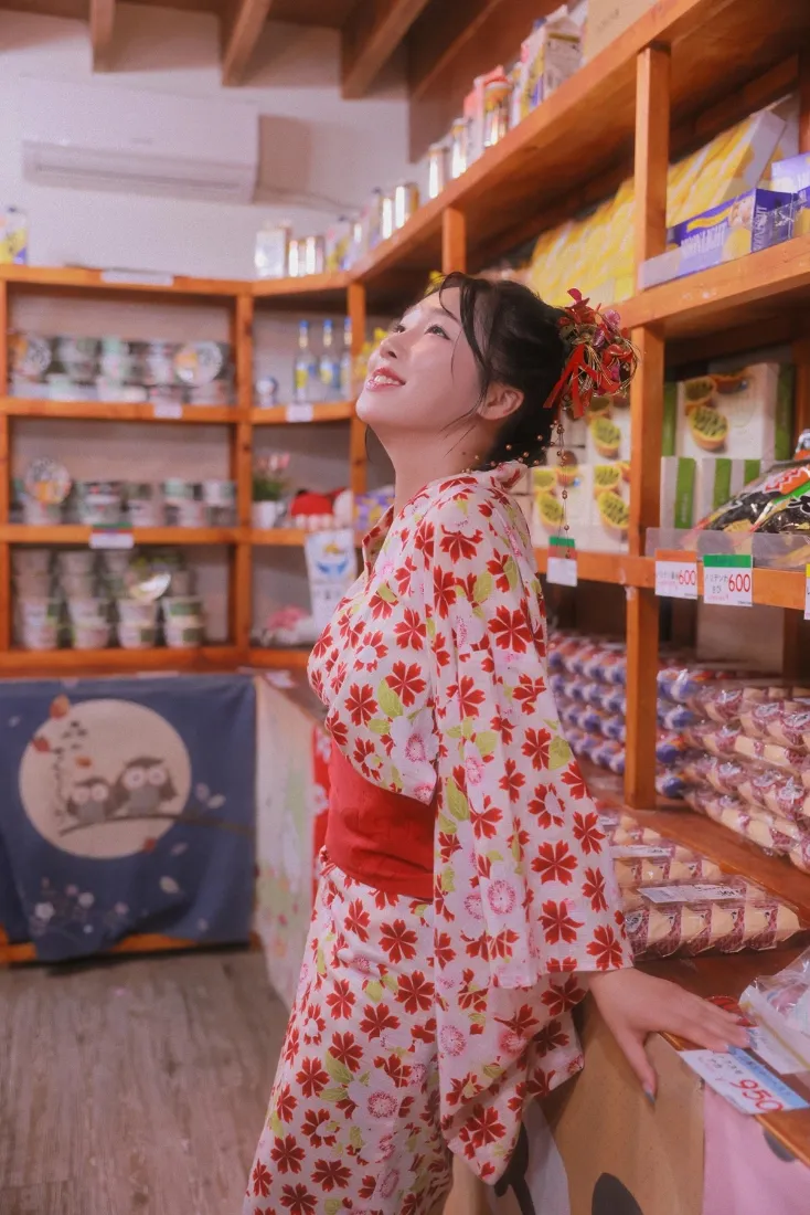 穿红花和服的女子在日式商店内仰头微笑，背景为木质货架。