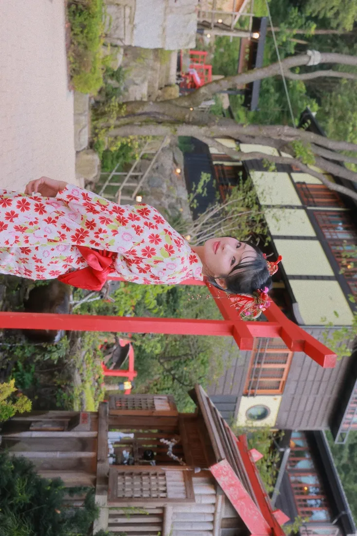 身着红樱花纹和服的少女在日式神社庭院中，背景有红色鸟居与传统建筑。