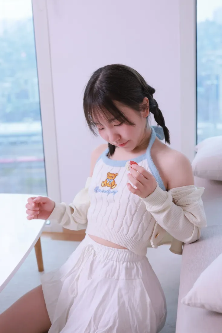 双马尾少女身着白色小熊刺绣套装，在明亮窗边居家环境中低头浅笑