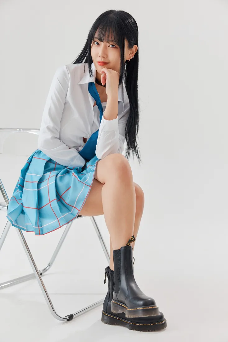身着JK制服的长发少女坐于透明折叠椅上，纯白简约影棚背景。