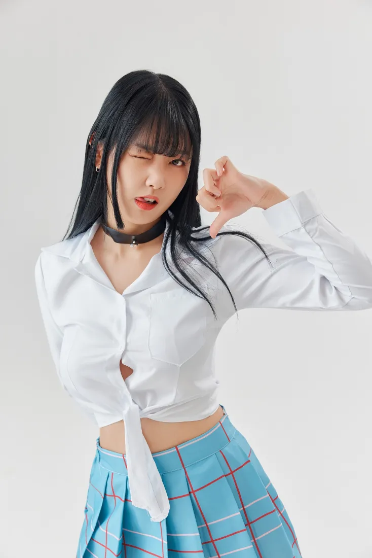 黑长发年轻女性穿打结白衬衫与蓝格纹短裙，wink俏皮摆姿势，浅灰纯色背景