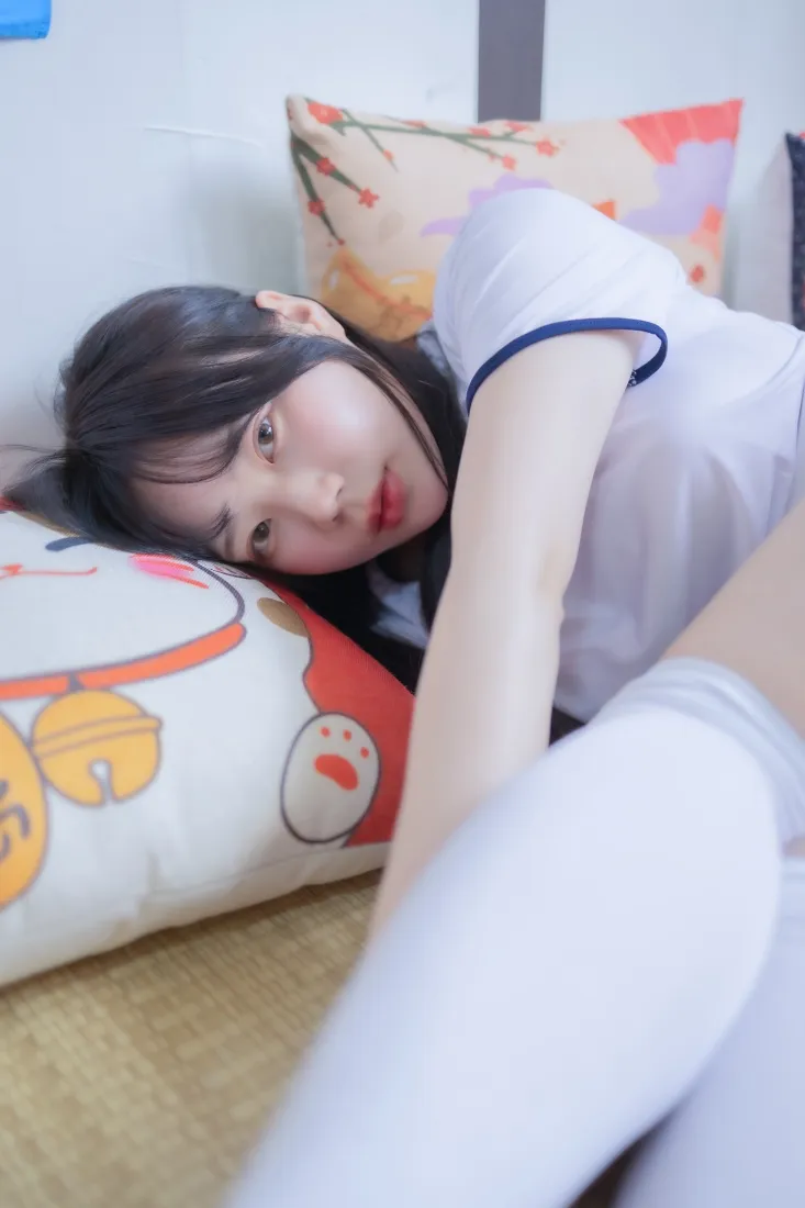 穿白校服白袜的年轻女生侧卧在卧室抱枕上，居家清纯风格