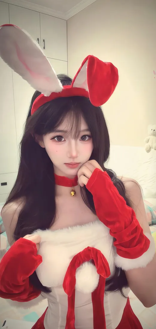室内自拍，长发女生戴红白兔耳发箍，穿圣诞风红白毛绒服饰，手托脸颊。
